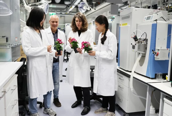 Image: From left to right: Moonyoung Kang, Lorenzo Caputi, Sarah O’Connor and Hai Anh Vu, holding Catharanthus roseus plants, are standing next to a liquid chromatography/mass spectrometry (LC/MS) system. This system is used to analyze metabolites in single cells. Credit: Angela Overmeyer